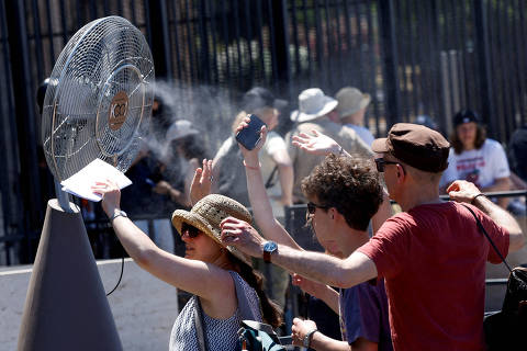Tourists stand in front of a cooling fan installed outside the Colosseum in during the heatwave in Rome, Italy, June 30, 2025. REUTERS/Remo Casilli ORG XMIT: FW1