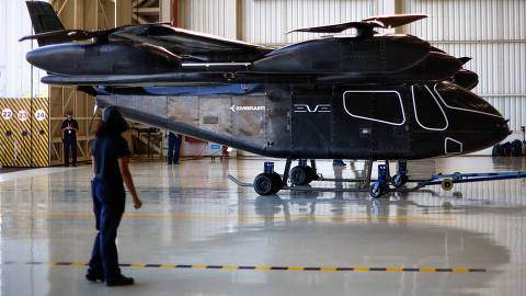 Employees stand near the full-scale prototype of electric vertical take-off and landing (eVTOL) aircraft developed by Eve Air Mobility, an Embraer group company, as it is presented for the first time in Gaviao Peixoto, Brazil July 3, 2024. REUTERS/Amanda Perobelli ORG XMIT: HFS-GGG-AMP08