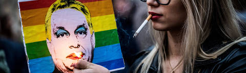 FILE PHOTO: A woman lights a cigarette placed in a placard depicting Hungary's Prime Minister Viktor Orban, during a demonstration, after the Hungarian parliament passed a law that bans LGBTQ+ communities from holding the annual Pride march and allows a broader constraint on freedom of assembly, in Budapest, Hungary, March 25, 2025. REUTERS/Marton Monus/File Photo ORG XMIT: FW1