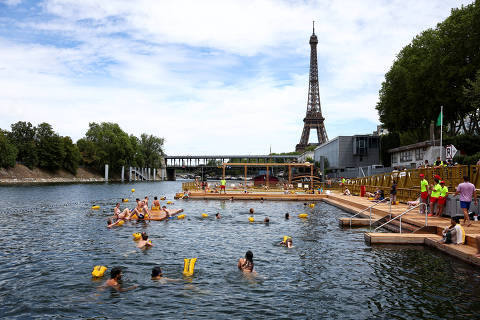People swim in the River Seine, with the Eiffel tower in the background, at the Grenelle site, opened to swimmers marking the first public bathing session in the capital's historic waterway, in Paris, France, July 5, 2025. REUTERS/Abdul Saboor      TPX IMAGES OF THE DAY ORG XMIT: LIVE