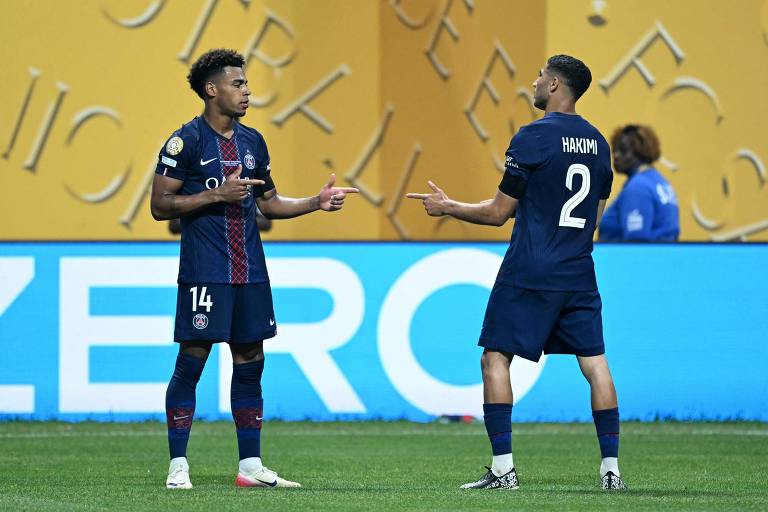 Dois jogadores do Paris Saint-Germain (PSG) estão em campo, discutindo entre si. O jogador à esquerda veste a camisa número 14 e o jogador à direita, a camisa número 2, que tem o nome 'Hakimi' nas costas. O fundo apresenta uma parede com a palavra 'ZERO' em destaque e uma cor amarela.