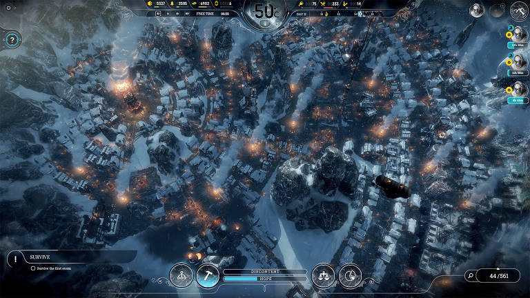 A imagem mostra a tela de um game em visão aérea, com uma cidade em um ambiente de inverno, com várias construções cobertas de neve. As luzes das casas estão acesas, criando um efeito brilhante em meio ao cenário escuro e frio. No canto inferior esquerdo, há uma barra de status com a palavra 'SURVIVE' e informações sobre recursos. O clima é severo, com temperaturas baixas indicadas na parte superior da tela.