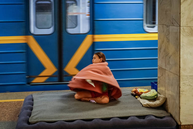 Menina se abriga em uma estação de metrô durante um alerta de ataque aéreo, em meio à ofensiva russa contra a Ucrânia, em Kiev