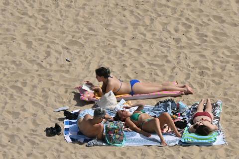 Sunbathers relax in the sunshine on Bournemouth Beach on the south coast of England on June 29, 2025. Temperatures in parts of England are expected to soar again Sunday after a second amber heat health alert in two weeks came into force on Friday. (Photo by JUSTIN TALLIS / AFP)