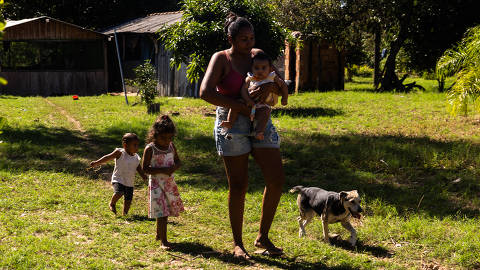 CORUMBÁ,MS, BRASIL 13.05.2025 - Rosemari Gomes de Souza, 24 anos, caminhava com suas filhas: Rafaela Gomes da Silva, em seu colo;  Jasmim Gomes da Silva (de vestido rosa) e Yasmim Gomes da Silva, que vinha logo atrás. Elas são moradoras da  comunidade da Barra do São Lourenço, localizada no município de Corumbá (MS), às margens do rio Paraguai. A região sofreu com incêndios de 2024, que devastaram parte da vegetação e impactaram na vida da comunidade. (Foto: Rafaela Araújo/Folhapress,Ambiente) *** EXCLUSIVO FOLHA***