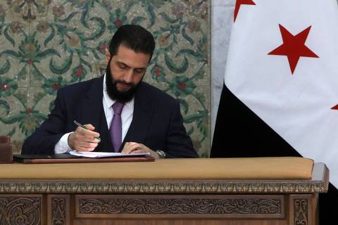 Syria's interim President Ahmad al-Sharaa signs the country's constitutional declaration, which will be enforced throughout a five-year transitional period, at the presidential palace in Damascus on March 13, 2025. Sharaa said he hoped the constitutional declaration would mark the start of 