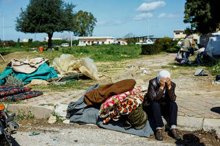 An Alawite woman sits with her belongings in the grounds of the Hmeimim Air Base, in Latakia, western Syria