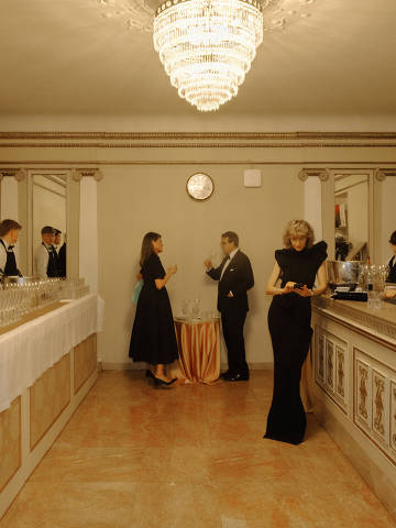 Visitors, dressed in formal attire, spend time in the Teatro alla Scala bar in Milan, Italy, Dec. 7, 2024. Few still button up tuxedos or roll on elbow-length gloves for a performance, as many venues have relaxed their dress codes, but tank tops, flip-flops and shorts is where Teatro alla Scala, the storied Milan opera house commonly known as La Scala, draws the line. ORG XMIT: XNYT0328