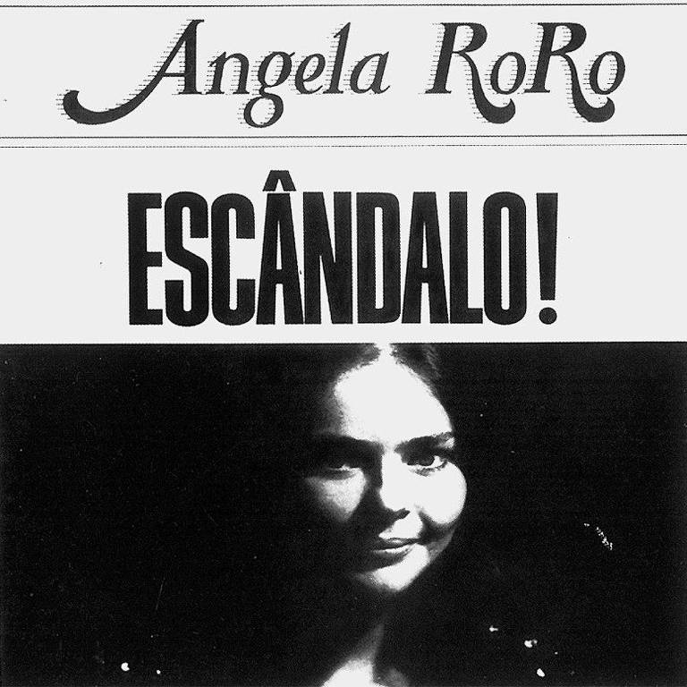 A imagem é uma capa de álbum em preto e branco, com o nome "Angela RoRo" no topo em uma fonte cursiva. Abaixo, em letras grandes e em negrito, está escrito "ESCÂNDALO!". A imagem apresenta uma mulher com um leve sorriso, iluminada de forma a destacar seu rosto, enquanto o fundo é escuro.
