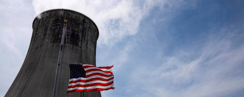 FILE PHOTO: The US flag flies at half mast in front of a coal-fired power plant's cooling tower at Duke Energy's Crystal River Energy Complex in Crystal River, Florida, U.S., March 26, 2021. Picture taken March 26, 2021. REUTERS/Dane Rhys/File Photo ORG XMIT: FW1