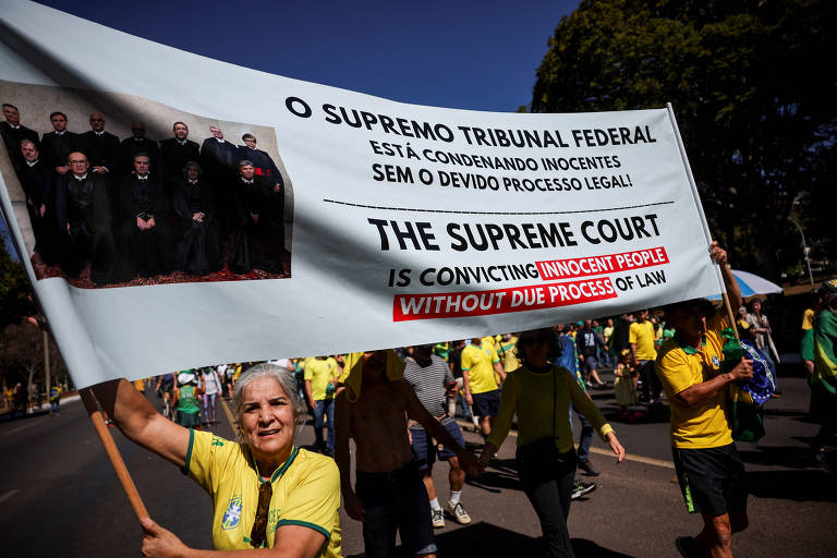 Pessoas seguram um cartaz contra o Supremo Tribunal Federal