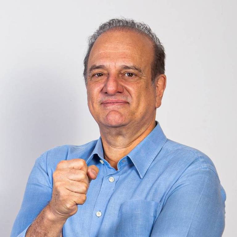 A imagem mostra um homem sorridente, com cabelo grisalho, vestindo uma camisa azul clara. Ele está fazendo um gesto de punho cerrado, como se estivesse determinado. Abaixo dele, há um texto em letras grandes que diz 'REVITALIZAR OS ESPORTES' em uma faixa amarela com fundo laranja.