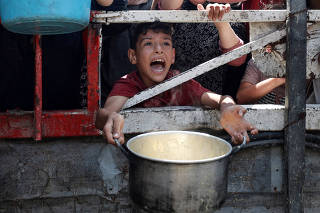 Palestinians wait to receive food from a charity kitchen, in Gaza City