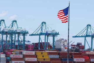 FILE PHOTO: The American flag flutters near a ship at Port of Los Angeles