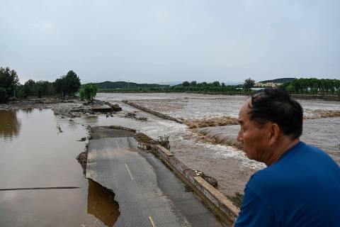 TOPSHOT - A damaged road is seen at a flooded area after heavy rains at Taishitun village in Miyun district, on the outskirts of Beijing on July 28, 2025. Torrential rain soaking northern China triggered a deadly landslide, burst riverbanks and washed away cars on July 28, with thousands of people forced to evacuate the days-long deluge. (Photo by Jade GAO / AFP)