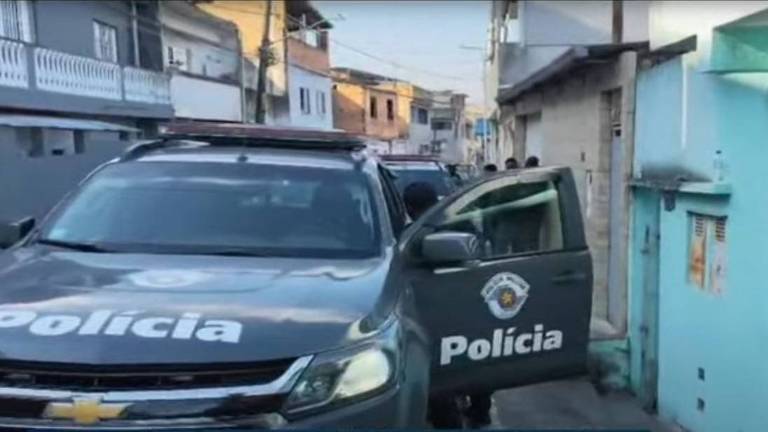 The image shows a police vehicle parked on a narrow street. The car is gray and has the word