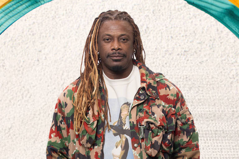 A imagem apresenta um homem com cabelo longo e dreadlocks, vestindo uma jaqueta camuflada e uma camiseta branca com uma estampa. Ele está posicionado em um fundo claro e texturizado, com elementos gráficos coloridos ao redor, incluindo folhas e uma faixa com o texto "A FAZENDA VAI INVADIR SUA ROTINA". O plan  é vibrante e chamativo, sugerindo uma promoção de um programa de televisão.