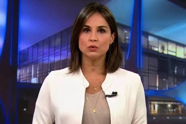 Em foto colorida, mulher de blazer branco apresenta programa em um estúdio
