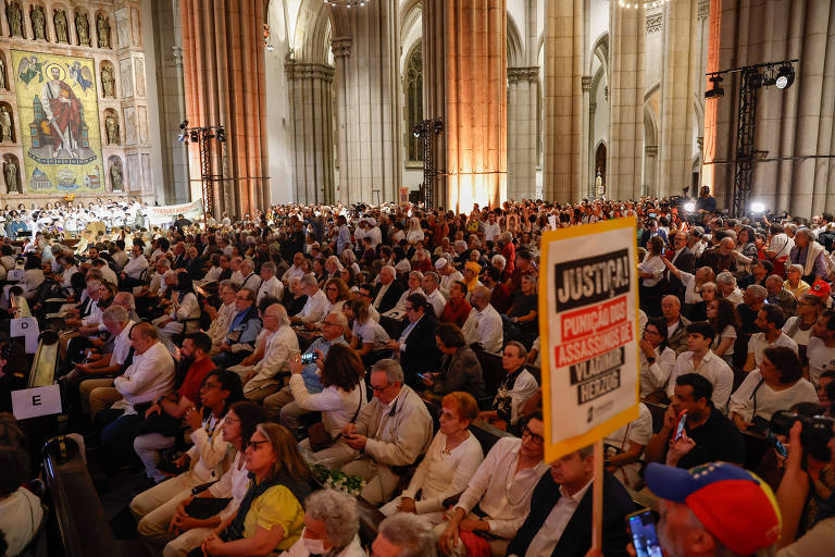 Público ergue cartazes com fotos de vítimas da ditadura em ato na Catedral da Sé.