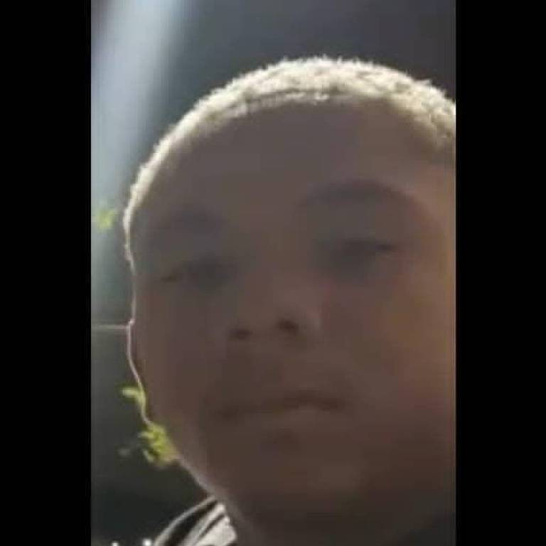 Un giovane con i capelli corti e chiari è mostrato in primo piano, mentre indossa una giacca scura. Lo sfondo è scuro, con un fascio di luce bianca in alto a sinistra.