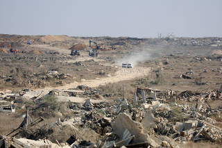 A machinery operates next to a Red Cross vehicle at an area within the so-called 