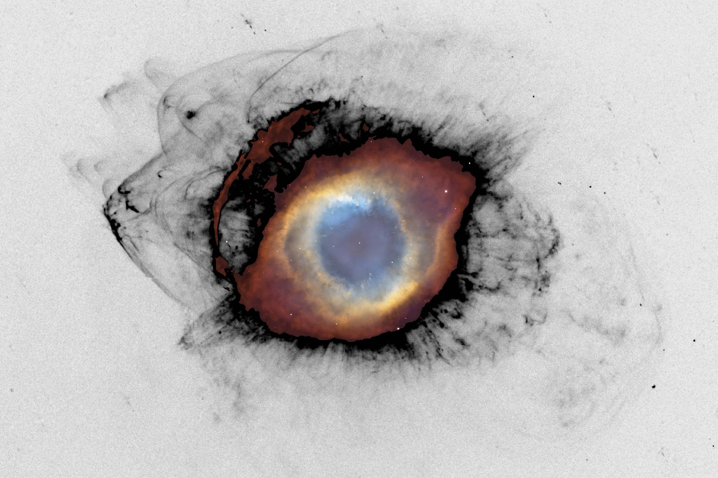 Imagem da Nebulosa Helix mostrando um núcleo azul central cercado por anéis concêntricos em tons de laranja, amarelo e vermelho, com filamentos escuros e nebulosos ao redor em fundo cinza.