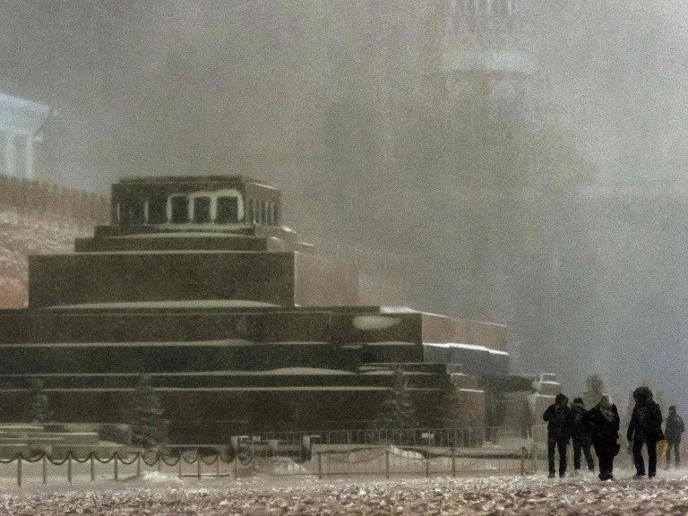 Pedestrians walk past the Lenin's Mausoleum, next to the Kremlin, under heavy snowfall in Moscow