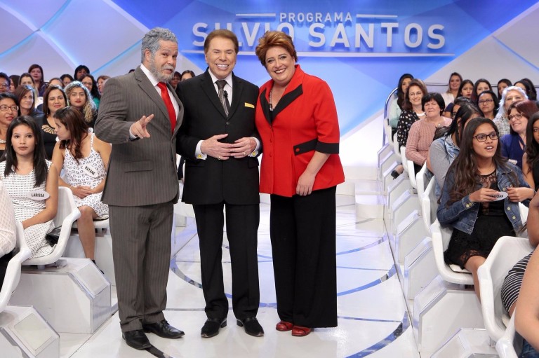 Silvio Santos com os humoristas humoristas Ênio Vivona, caracterizado como o presidente Lula, e Mila Ribeiro de Dilma Rousseff, durante um de seus programas de auditório.